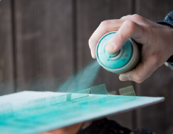 Can of aerosal adhesive being sprayed onto a surface
