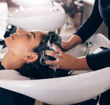 Woman having her hair washed with shampoo in a hair salon sink