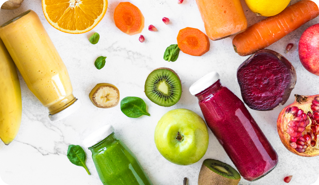 Fruit and vegetable beverages in reusable glass bottles on a table with fruits and vegetables
