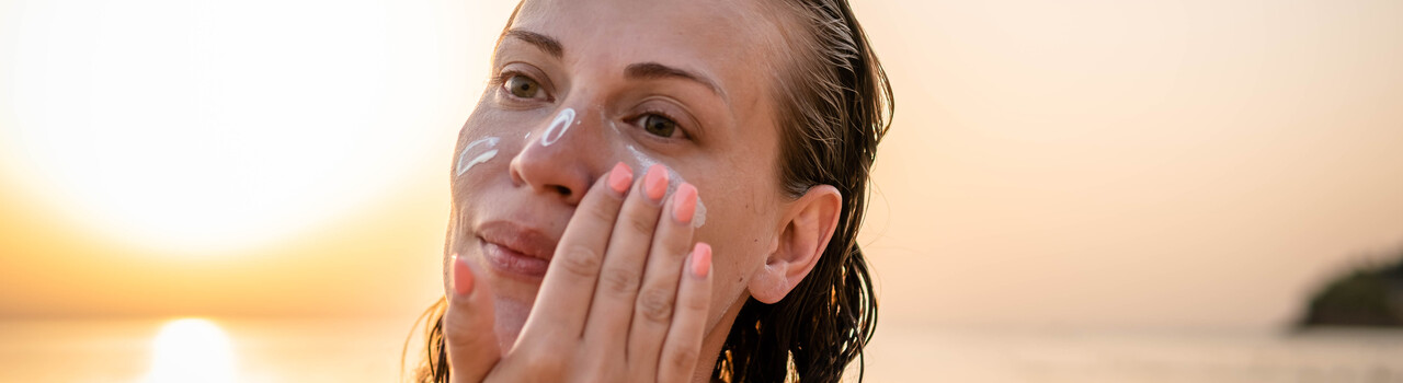 A woman applying sunscreen on the beach