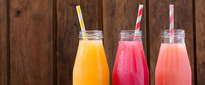 Three different kinds of fruit juice in bottles with straws