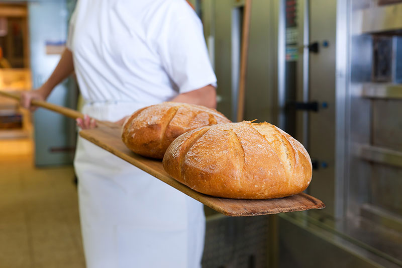 Taking fresh bread from oven