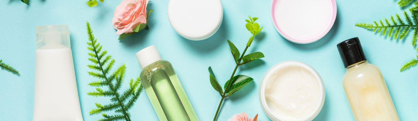 Beauty products arranged with green leaves