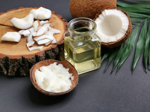 A coconut split with a jar of its oil