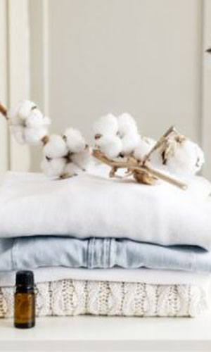 Laundry folder with cotton plant and essential oils on a table