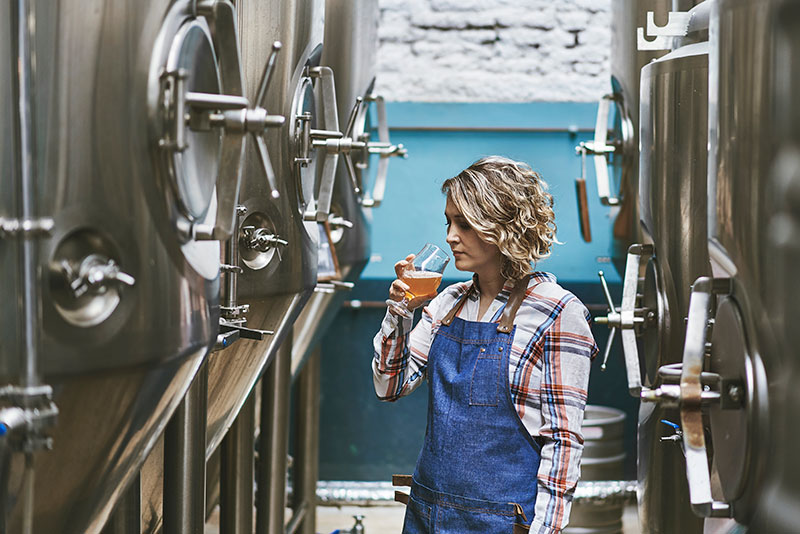 Female Brewer Testing Beer in Brewery