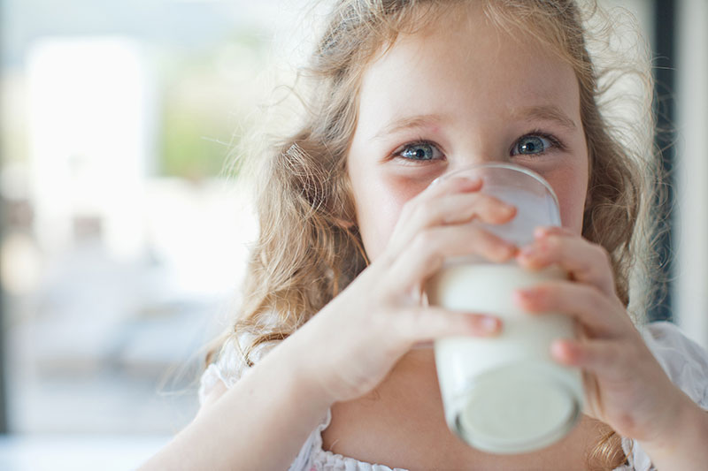 A young child enjoying a glass of milk