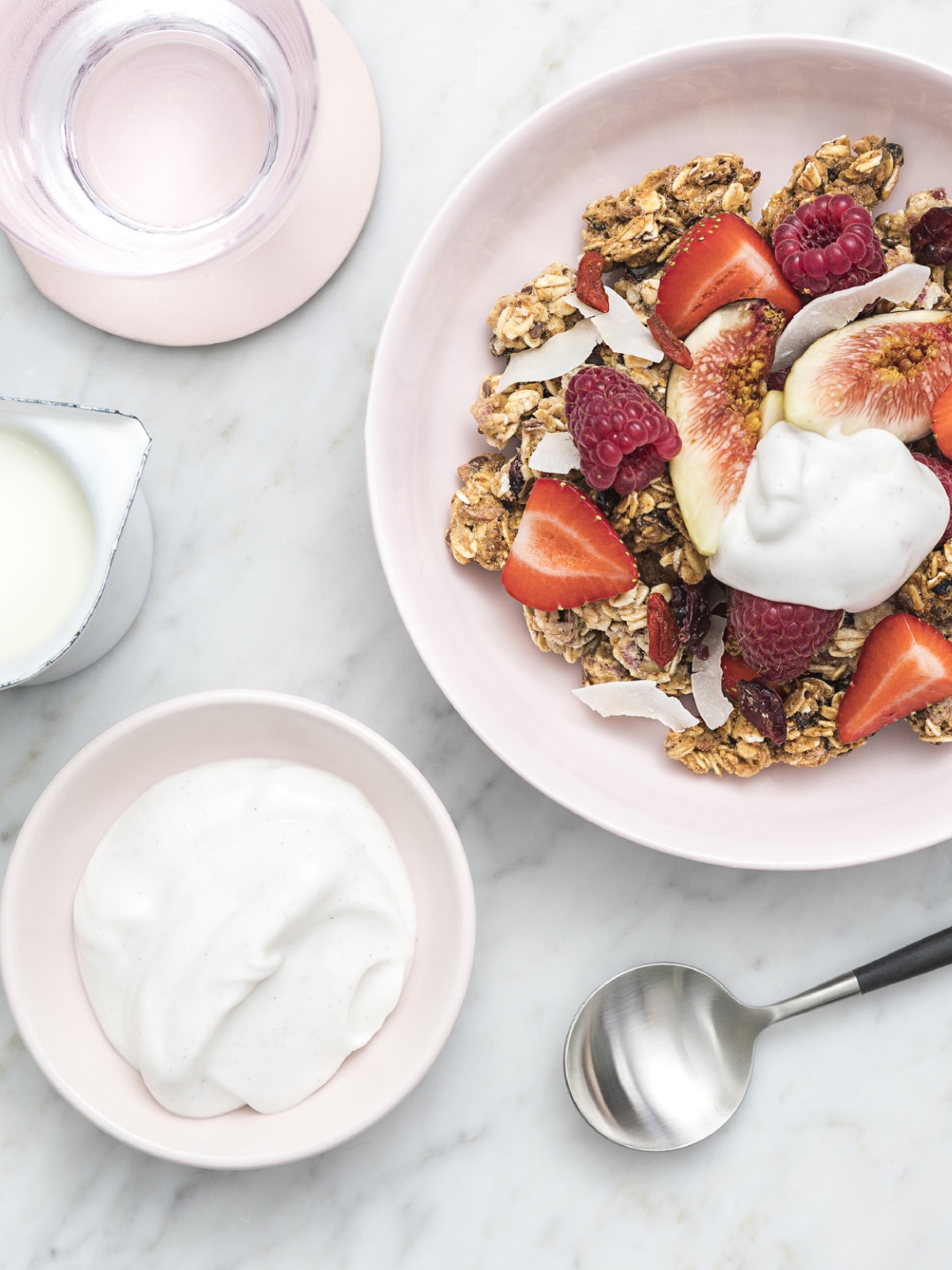 A bowl of granola, strawberries, raspberries, and coconut with a dallop of plant-based cream on top
