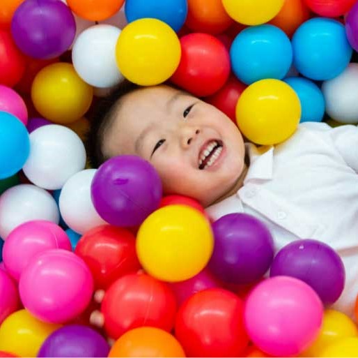 Laughing child surrounded by colorful plastic balls