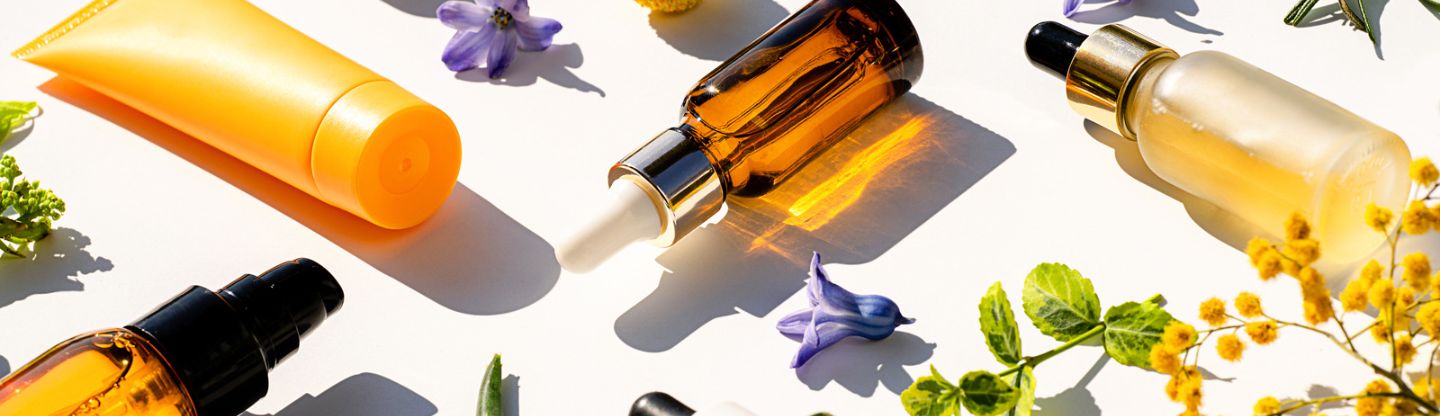 Essential oils and creams on a table surrounded by flowers