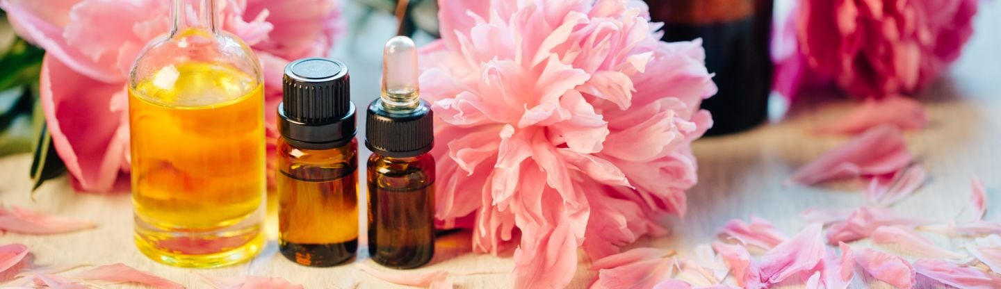 Essential oil bottles next to flowers on a table