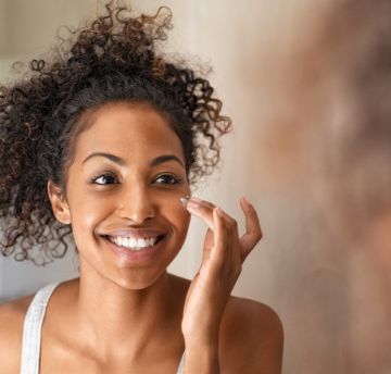 Woman applying cream to her cheek