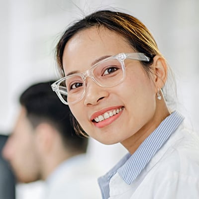 A lab scientist in PPE smiling at the camera