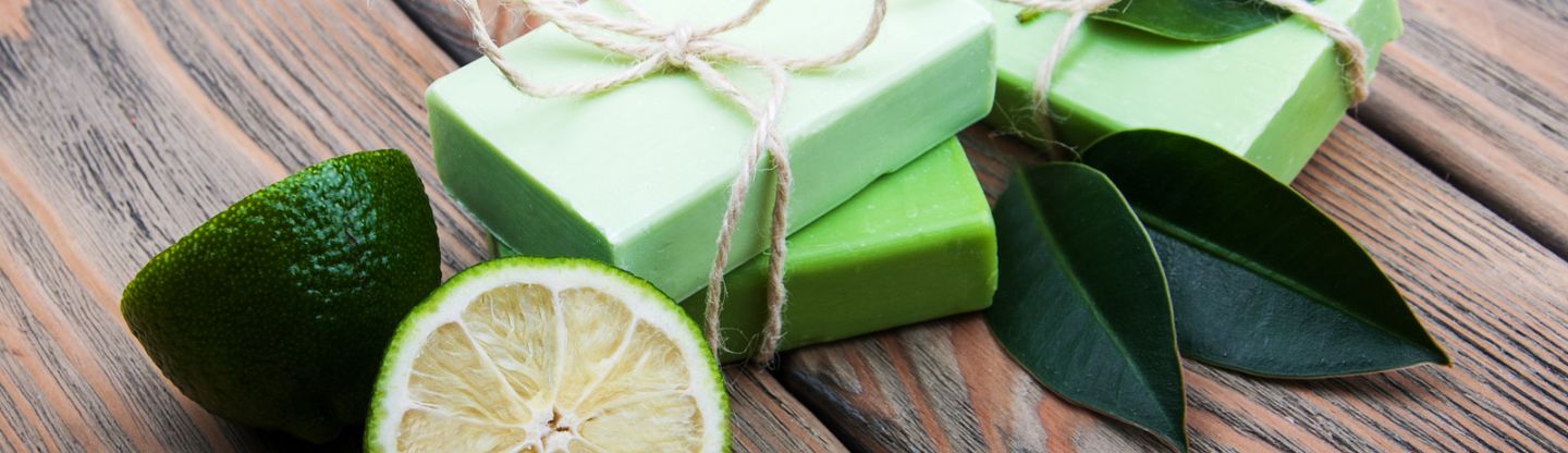 Limes and green bars of soap on a wooden surface