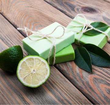 Limes and green bars of soap on a wooden surface