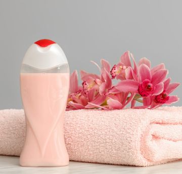 Shampoo bottle next to a pink towel with flowers on top