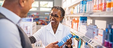 A pharmacist helping a customer shop for topical solutions off the shelf.