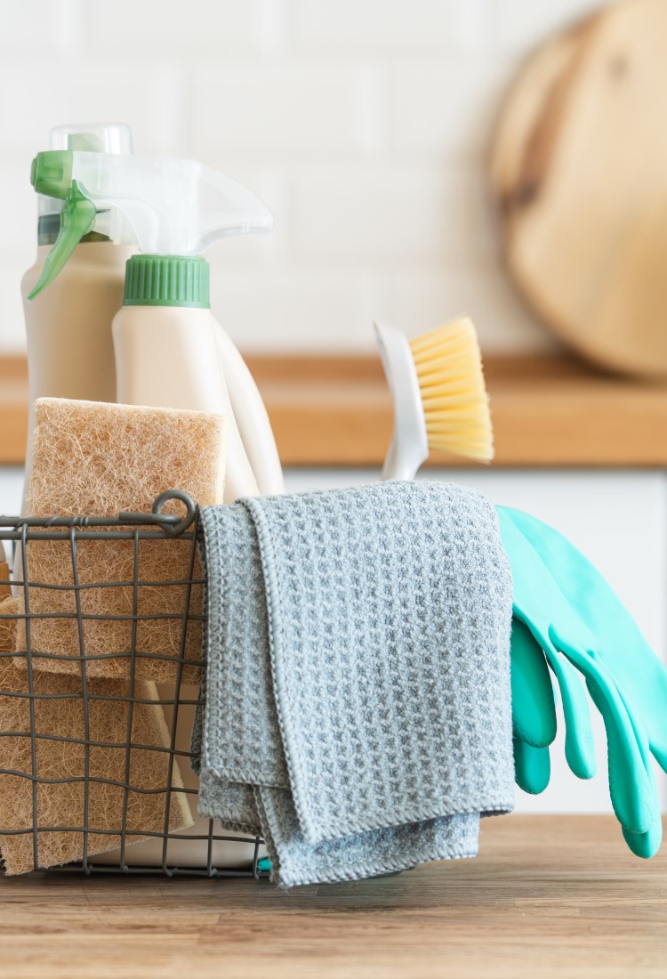 Sustainable cleaning supplies in a wire basket sitting on a kitchen counter top